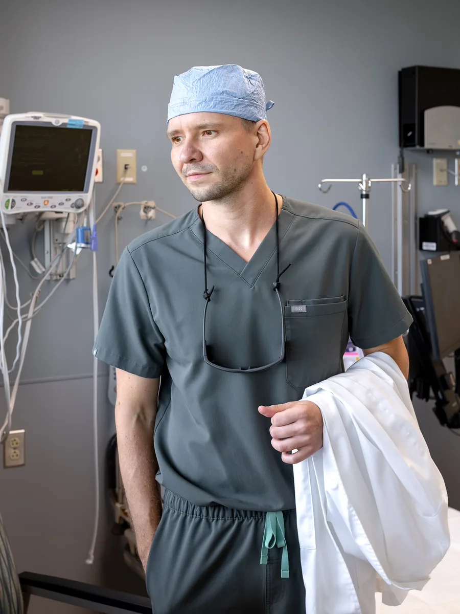 Dr. Yaranov in scrubs and a surgical cap, holding his white coat